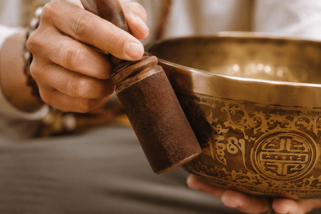 Close up of a mallet striking a metal bowl for vibrational resonance and stress relief.